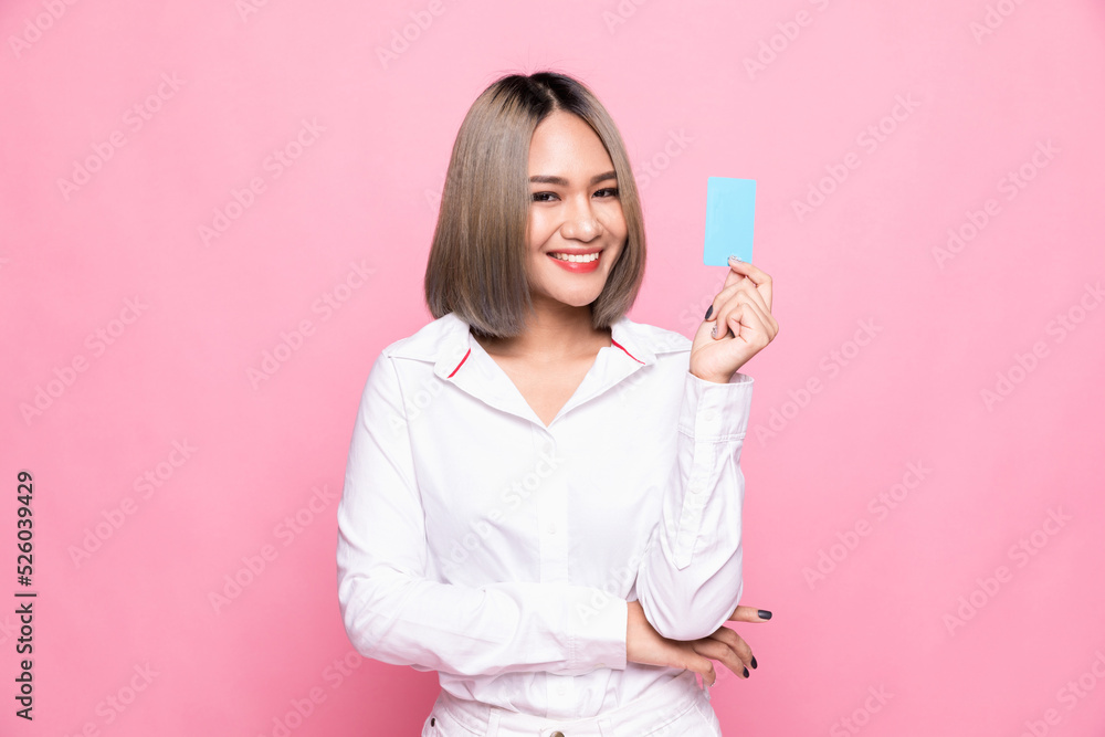 Shopping concept. Young Asian woman smiling and showing plastic credit card, paying contactless, standing over pink background Shopping concept. Young Asian woman smiling and showing plastic credit card, paying contactless, standing over pink background