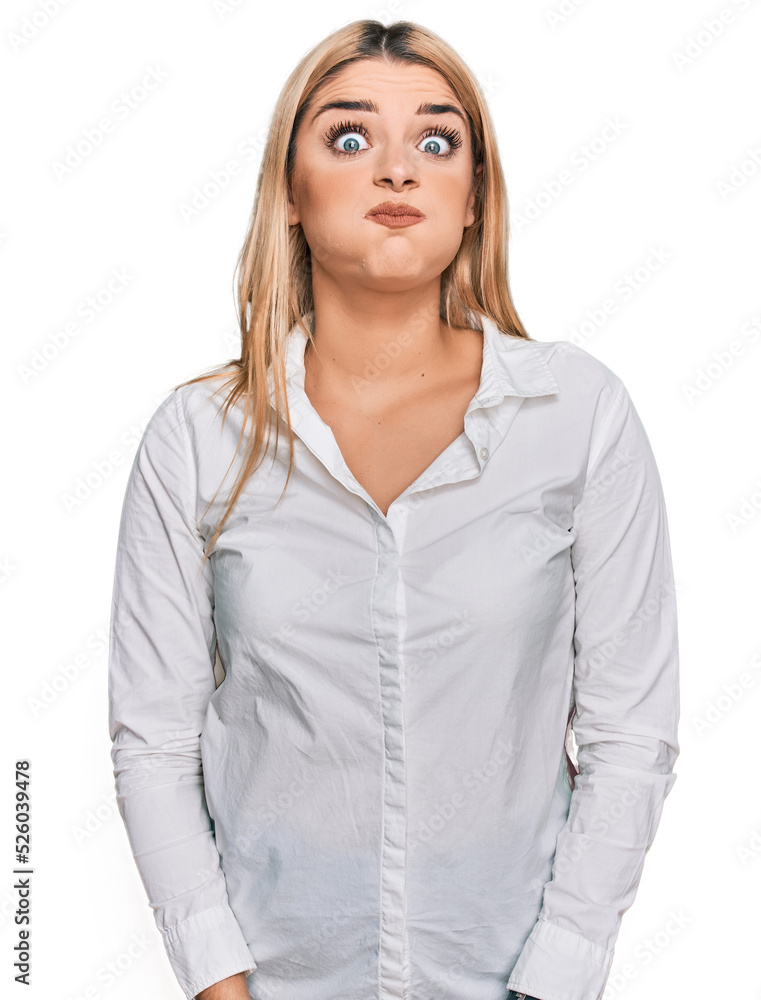 Young caucasian woman wearing casual clothes puffing cheeks with funny face. mouth inflated with air, crazy expression. Young caucasian woman wearing casual clothes puffing cheeks with funny face. mouth inflated with air, crazy expression.