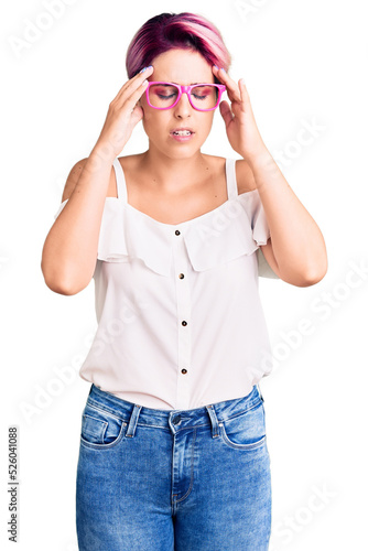 Young beautiful woman with pink hair wearing casual clothes and glasses with hand on head for pain in head because stress. suffering migraine. © Krakenimages.com