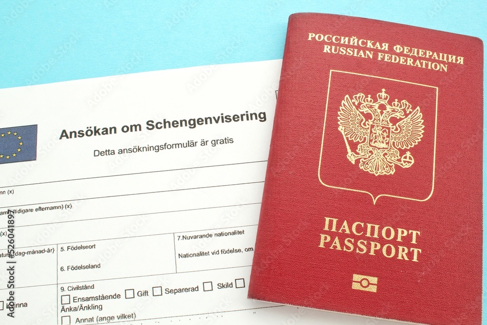 Schengen visa application form in Swedish language and passport on blue background. Prohibition and suspension of visas for Russian tourists to travel to European Union and the Baltic States concept Schengen visa application form in Swedish language and passport on blue background. Prohibition and suspension of visas for Russian tourists to travel to European Union and the Baltic States concept
