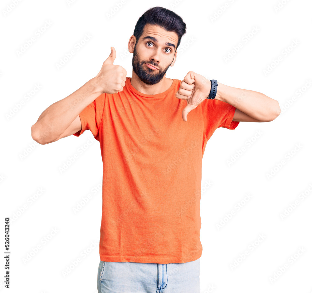 Young handsome man with beard wearing casual t-shirt doing thumbs up and down, disagreement and agreement expression. crazy conflict Young handsome man with beard wearing casual t-shirt doing thumbs up and down, disagreement and agreement expression. crazy conflict