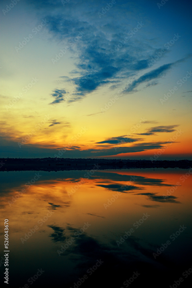 A wonderful dawn on the river with a reflection in the water. vertical