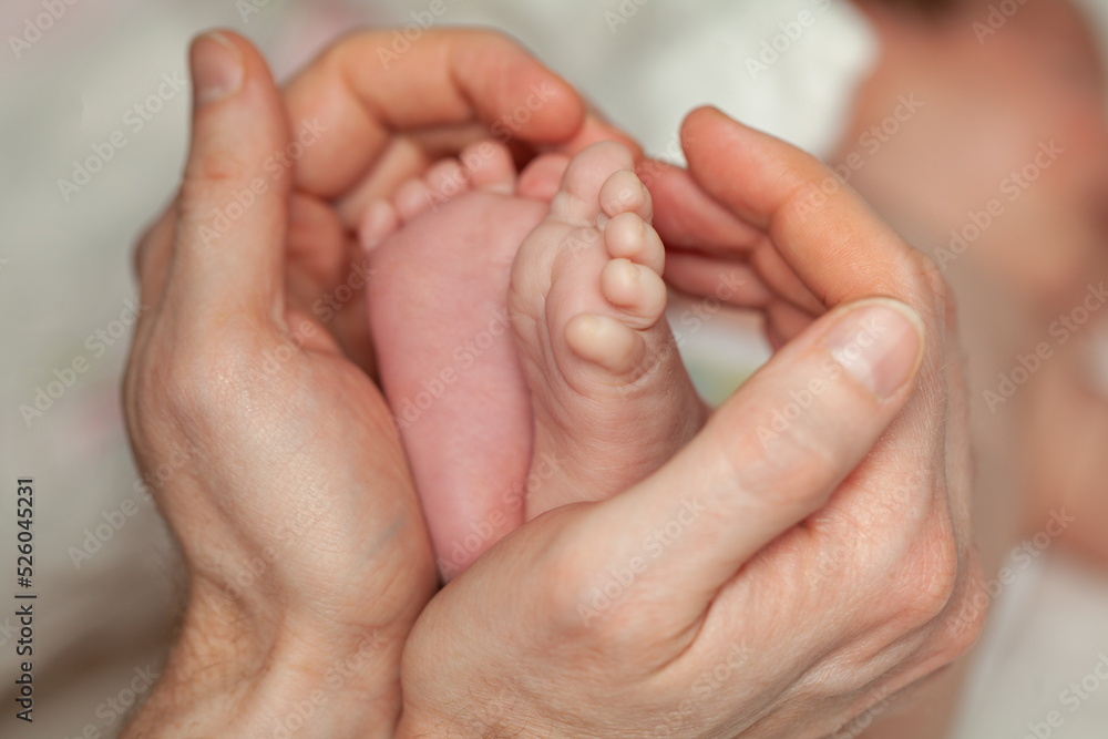 Newborn cute feet in young father hands. Lovely, emotional moment closeup Newborn cute feet in young father hands. Lovely, emotional moment closeup