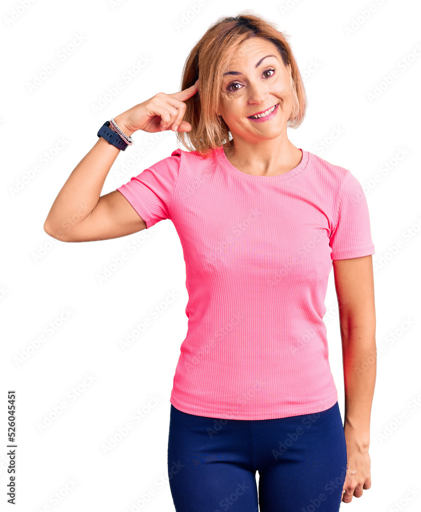 Young blonde woman wearing sportswear smiling pointing to head with one finger, great idea or thought, good memory Young blonde woman wearing sportswear smiling pointing to head with one finger, great idea or thought, good memory