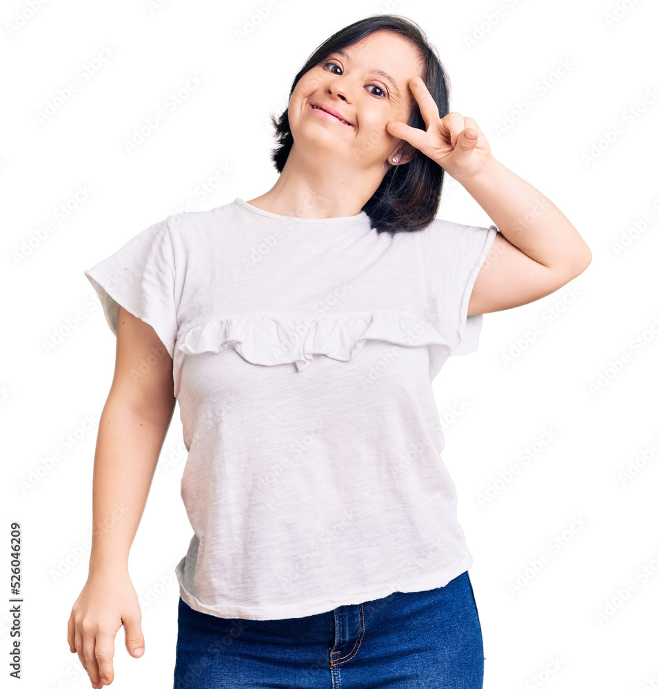 Brunette woman with down syndrome wearing casual white tshirt doing peace symbol with fingers over face, smiling cheerful showing victory Brunette woman with down syndrome wearing casual white tshirt doing peace symbol with fingers over face, smiling cheerful showing victory