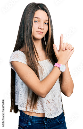 Young brunette girl with long hair wearing white shirt holding symbolic gun with hand gesture, playing killing shooting weapons, angry face