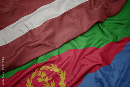 waving colorful flag of eritrea and national flag of latvia.