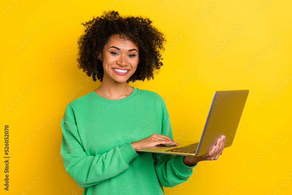 Portrait of pretty cheerful girl look camera hold netbook toothy smile isolated on yellow color background Portrait of pretty cheerful girl look camera hold netbook toothy smile isolated on yellow color background