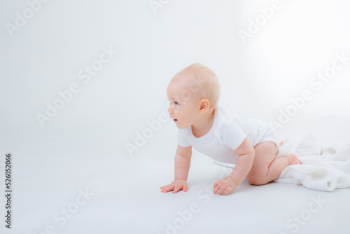 baby boy in a white bodysuit crawling on a white background
