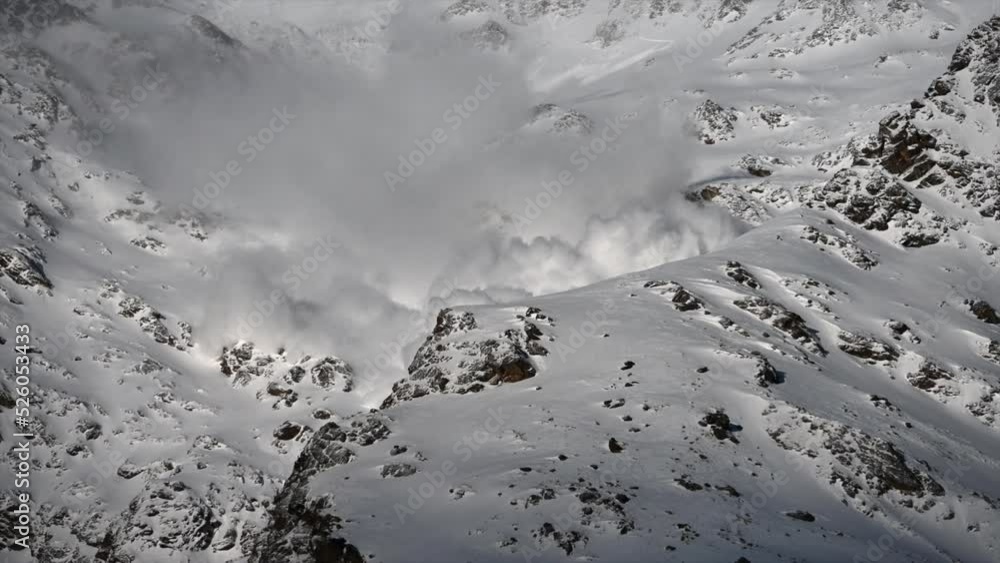 A large avalanche Made with power goes down a rocky Swiss alps Mountain next to ski slopes, science