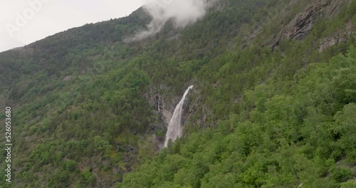 Stodnafossen waterfall on mountainside covered in lush vegetation; aerial photo