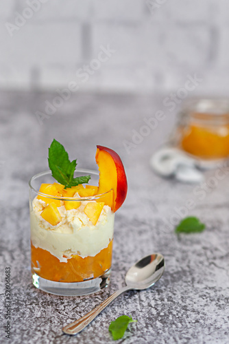 Peach fruit dessert in a glass cup with curd cream and peach jam.