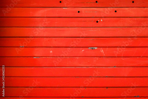 Striped metal textured wall painted in a red, background, abstract horizontal lines, dirty steel colored shutter garage door, grunge texture and pattern.