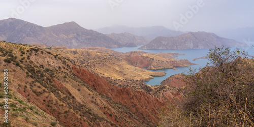 Panoramic landscape view of colorful Nurek or Norak dam lake and valley between Dushanbe and Khatlon regions in Tajikistan on overcast summer day