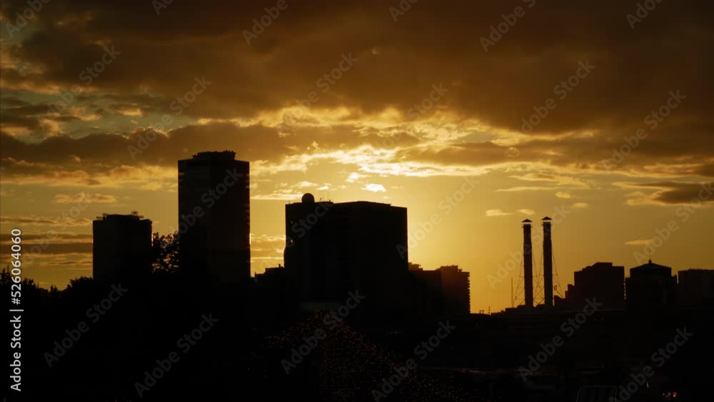 Sunset in the city. Silhouettes of industrial buildings with factory chimneys Sunset in the city. Silhouettes of industrial buildings with factory chimneys
