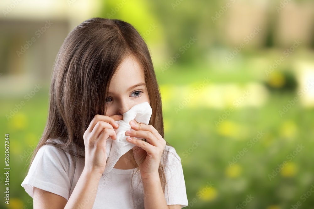 Young pretty woman blowing nose in front of blooming tree. Spring allergy concept. Sick people allergy or virus influenca concept. Young pretty woman blowing nose in front of blooming tree. Spring allergy concept. Sick people allergy or virus influenca concept.