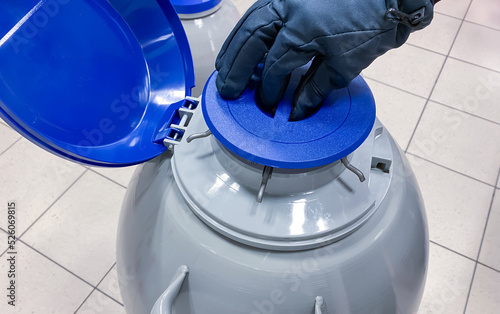 A scientist opening a tank with liquid nitrogen. Liquid nitrogen is used for long-term storage of biological samples like cancer cells for research purposes and sperm for in vitro fertilization 