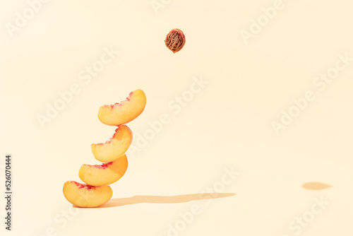 Authentic fruits composition made of peach slices and pit with sunlit shadows against bright beige background. Surreal creative food concept.