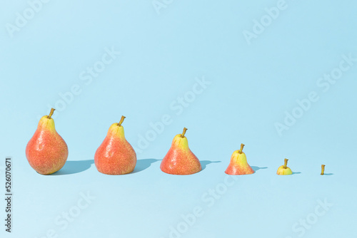 Photo Fresh pears in descending size order, sinking in bright blue background