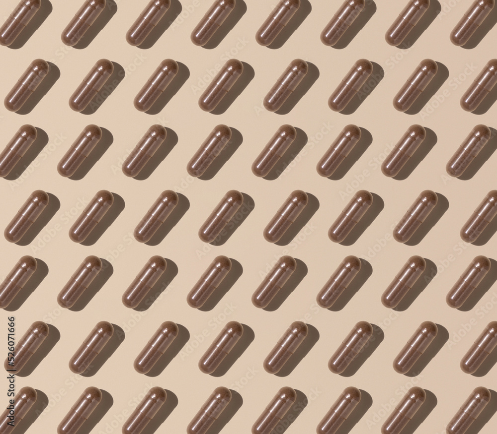 Creative pattern with capsules on light beige top view, hard shadows. Taking supplements Creative pattern with capsules on light beige top view, hard shadows. Taking supplements