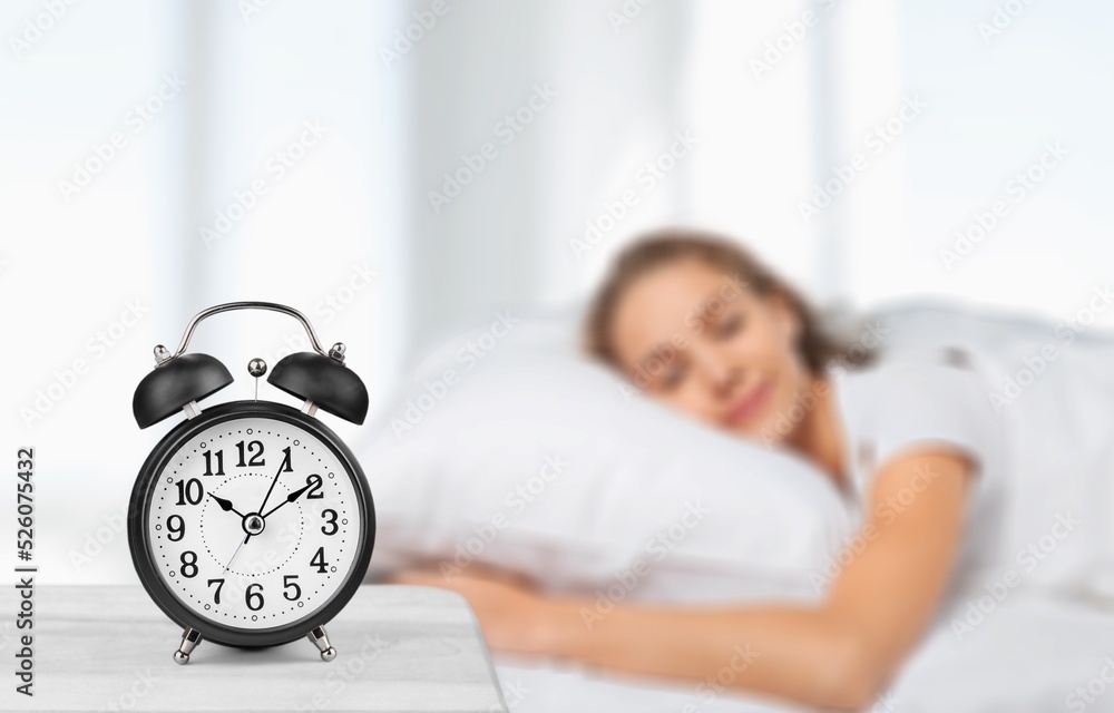 Classic alarm clock on bedside table in bedroom, with happy peaceful