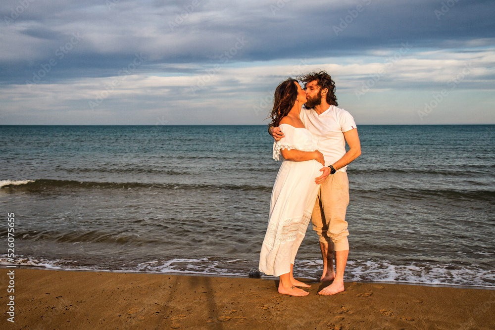 A pregnant couple on a beach during sunset A pregnant couple on a beach during sunset
