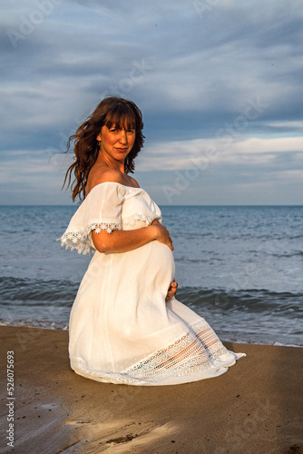 A young pregnant woman on a beach touching her pregnancy belly