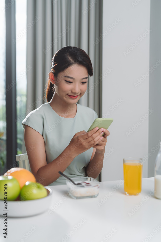 young woman using her mobile phone while having breakfast young woman using her mobile phone while having breakfast