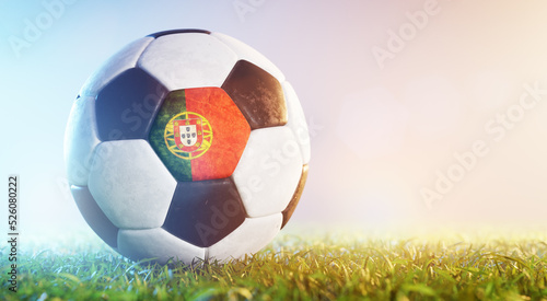 Football soccer ball with flag of Portugal on grass