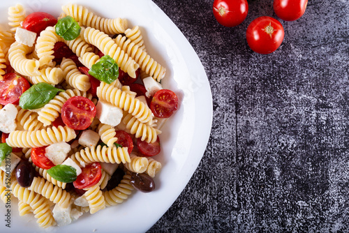 Greek-style pasta served with feta cheese, tomatoes and black olives. Typical dish of Greek and Mediterranean cuisine, suitable for a vegetarian diet.