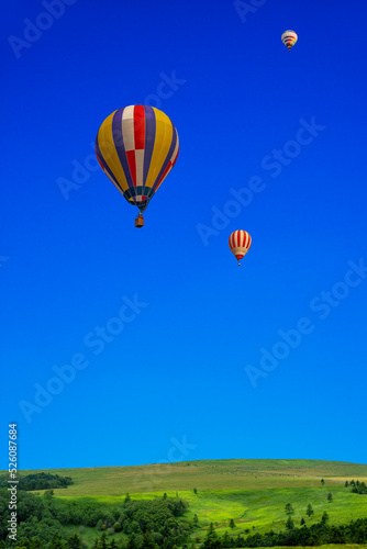 青空を背景にした地平線の見える草原と熱気球 © chikala