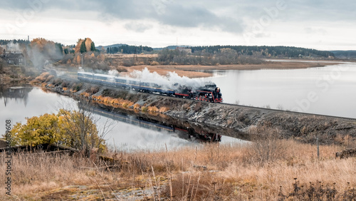 Fototapeta Naklejka Na Ścianę i Meble -  Russia Karelia is city of Sortavala Historic old steam train with a wagon rides along the embankment of Lake Ladoga