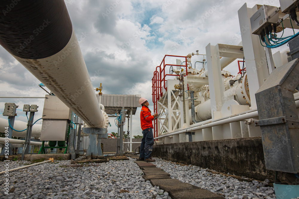 Obraz premium Male worker inspection at steel long pipes and pipe elbow in station oil factory during refinery valve of visual check record pipeline