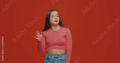 Doubtful young girl showing so-so hand gesture, doubting on orange studio background. Uncertainty, ambivalent estimate