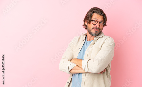 Senior dutch man isolated on pink background with arms crossed and looking forward