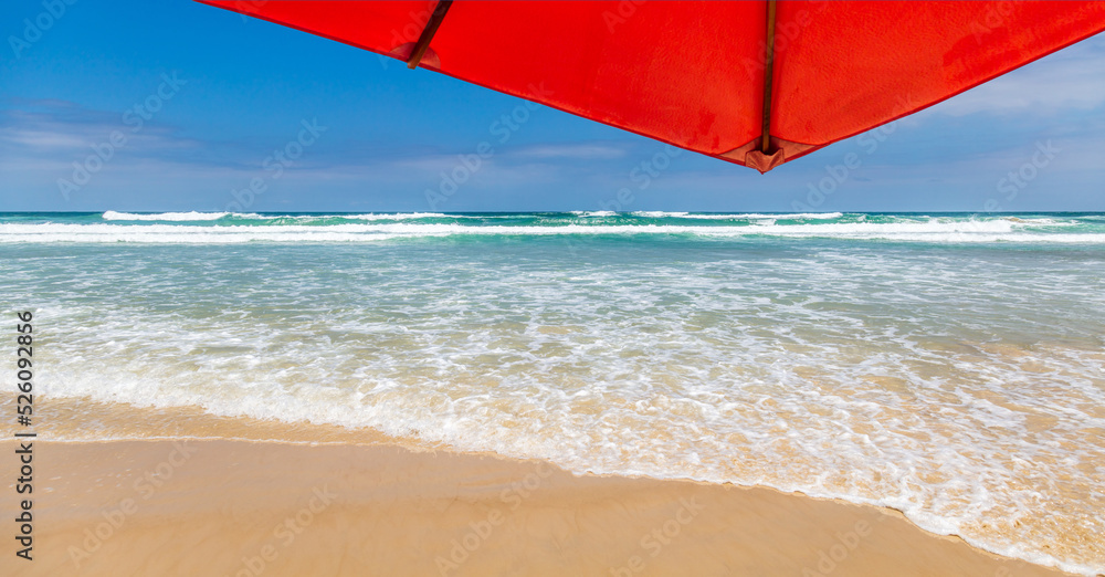 On the beach under the umbrella.