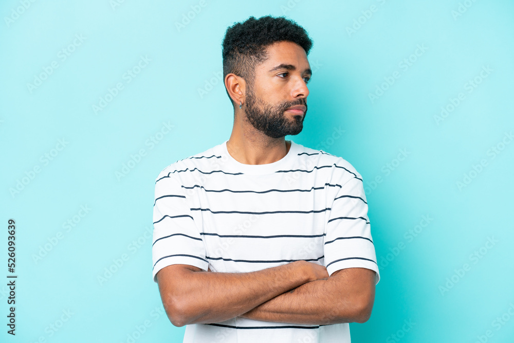 Young Brazilian man isolated on blue background keeping the arms crossed Young Brazilian man isolated on blue background keeping the arms crossed