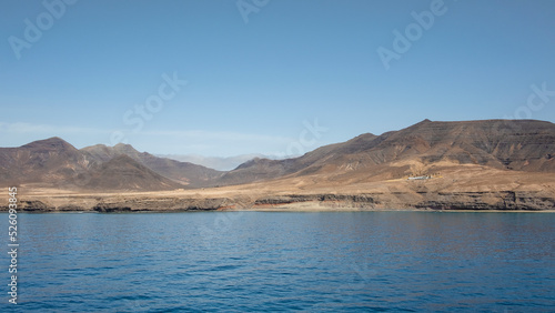 Approaching the island of Fuerteventura from the Atlantic Ocean  views towards the arid desert-like volcanic landscape with few scattered farms  remote beaches and rough terrain  Canary Islands  Spain