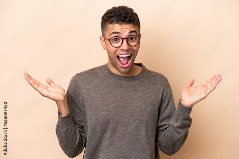 Fototapeta premium Young Brazilian man isolated on beige background with shocked facial expression