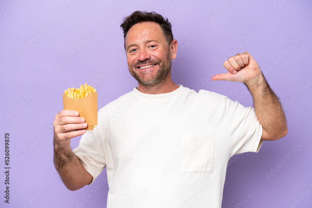 Middle age caucasian man holding fried chips isolated on purple bakcground proud and self-satisfied Middle age caucasian man holding fried chips isolated on purple bakcground proud and self-satisfied