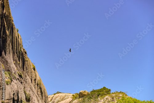black bird flying in blue sky, rocks in the mountains, rocks with mosses in the mountains, landscape in the mountains, Araruna, Brazil, mountains in Brazil, mountain climbing in Brazil 