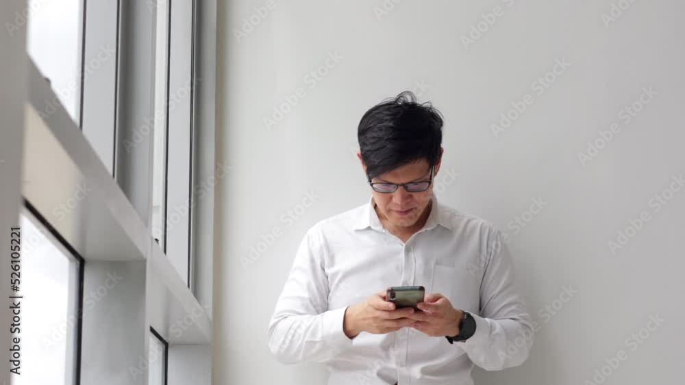 Handsome office worker hold mobile phone in hand call to girlfriend by mobile phone looking out through window at modren office balcony in relax time. Handsome office worker hold mobile phone in hand call to girlfriend by mobile phone looking out through window at modren office balcony in relax time.