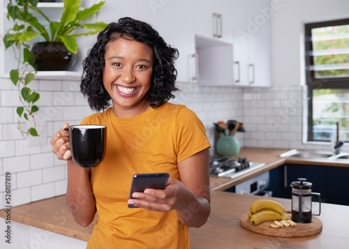 A young multi-ethnic woman smiles at the camera eating breakfast in the kitchen photo