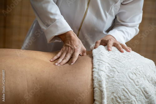 Um profissional fazendo massagem terapêutica nas costas do paciente que está deitado na maca.