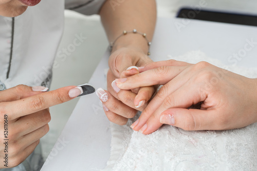 latina manicurist  performing a correct filing of the nails to give them shape and correct the irregular edges. girl performing filing practice for manicure.
