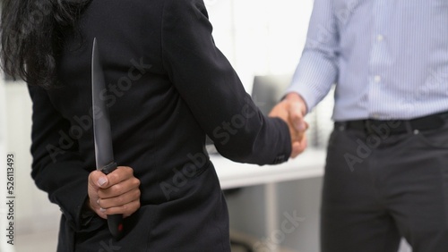 Fotografi Back view of businesswoman shaking hands with another businessman while holding a knife behind his back