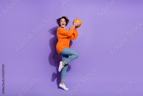 Full length body size view of nice childish girl jumping hold pumpkin having fun isolated on bright purple violet color background