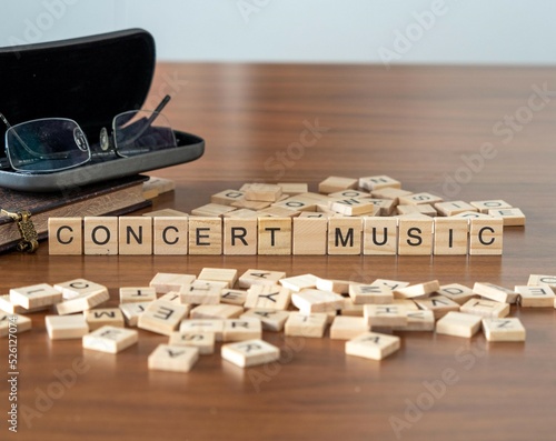 concert music word or concept represented by wooden letter tiles on a wooden table with glasses and a book