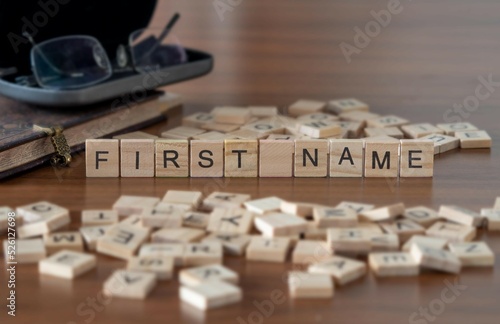 first name word or concept represented by wooden letter tiles on a wooden table with glasses and a book photo