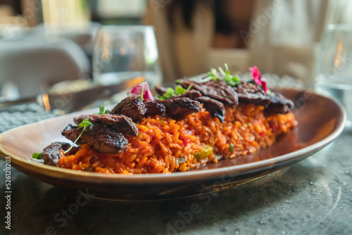 Primer plano churrasco angus sobre arroz amarillo con verduras, toques de plátano maduro y aguacate. Concepto de comida de alto nivel photo